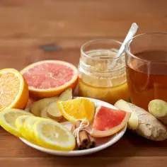 Herbata z imbirem, cytryną, pomarańczą, grejpfrutem, miodem i czosnkiem na drewnianym tle.